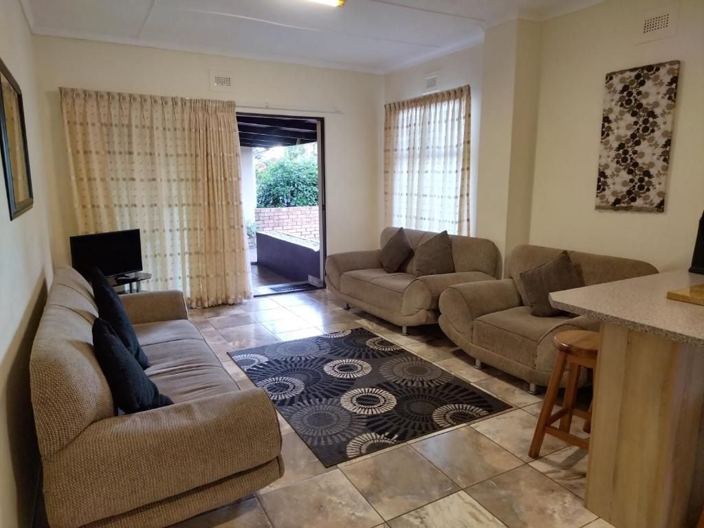 A living room with a sofa, a coffee table, and a TV. There is a door leading to an outdoor area.