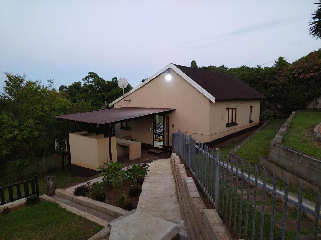 A single-story house with a covered porch, a satellite dish, and a small garden area.
