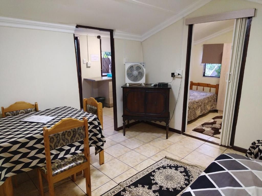 Une pièce comprenant une table à manger, des chaises, un ventilateur, un miroir et un lit.