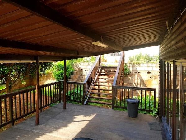 A covered outdoor area with a wooden staircase leading to a stone structure. - Klein Paradys (Port Shepstone)