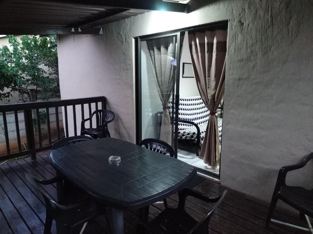 Una terrassa coberta amb taula i cadires, una porta corredissa de vidre i vista d'un llit amb un disseny decoratiu.