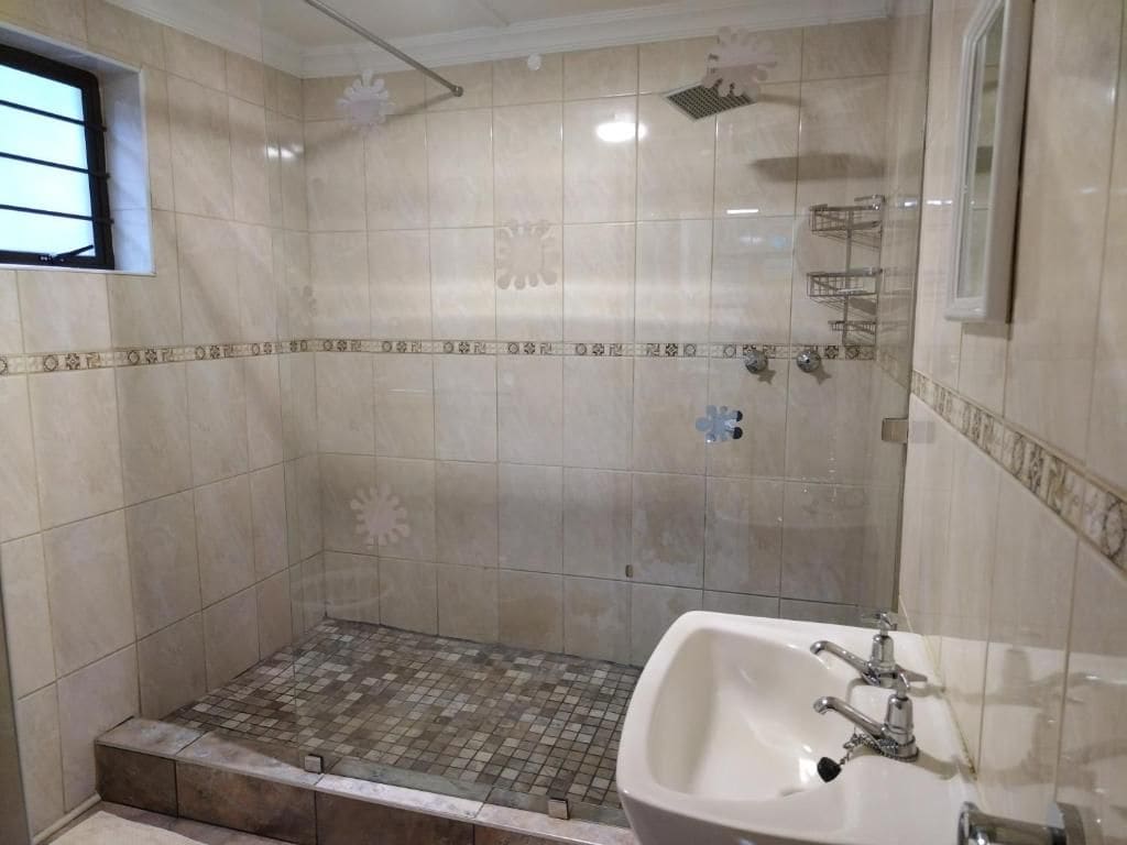 A bathroom with a shower, a sink, and tiled walls.