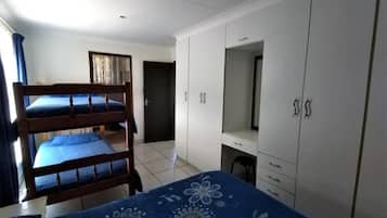 A room with bunk beds, a desk, and a wardrobe.
