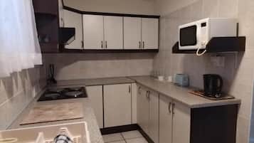 Eine kompakte Küche mit Mikrowelle, Toaster und Kaffeemaschine.