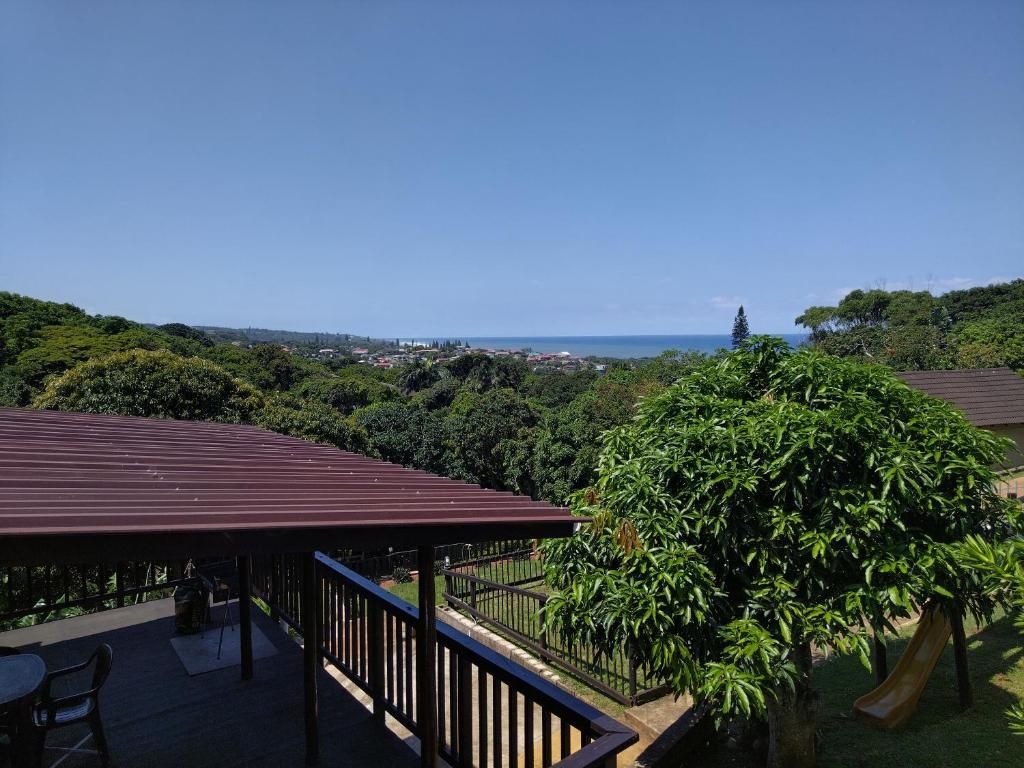 Ein überdachter Außenbereich mit Blick auf das Meer, umgeben von Grün.