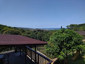 Un espacio al aire libre techado con vista al mar, rodeado de vegetación.