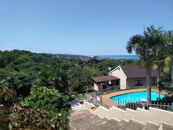 Una propiedad residencial con piscina, una escalera que lleva a una casa y vistas a la costa.
