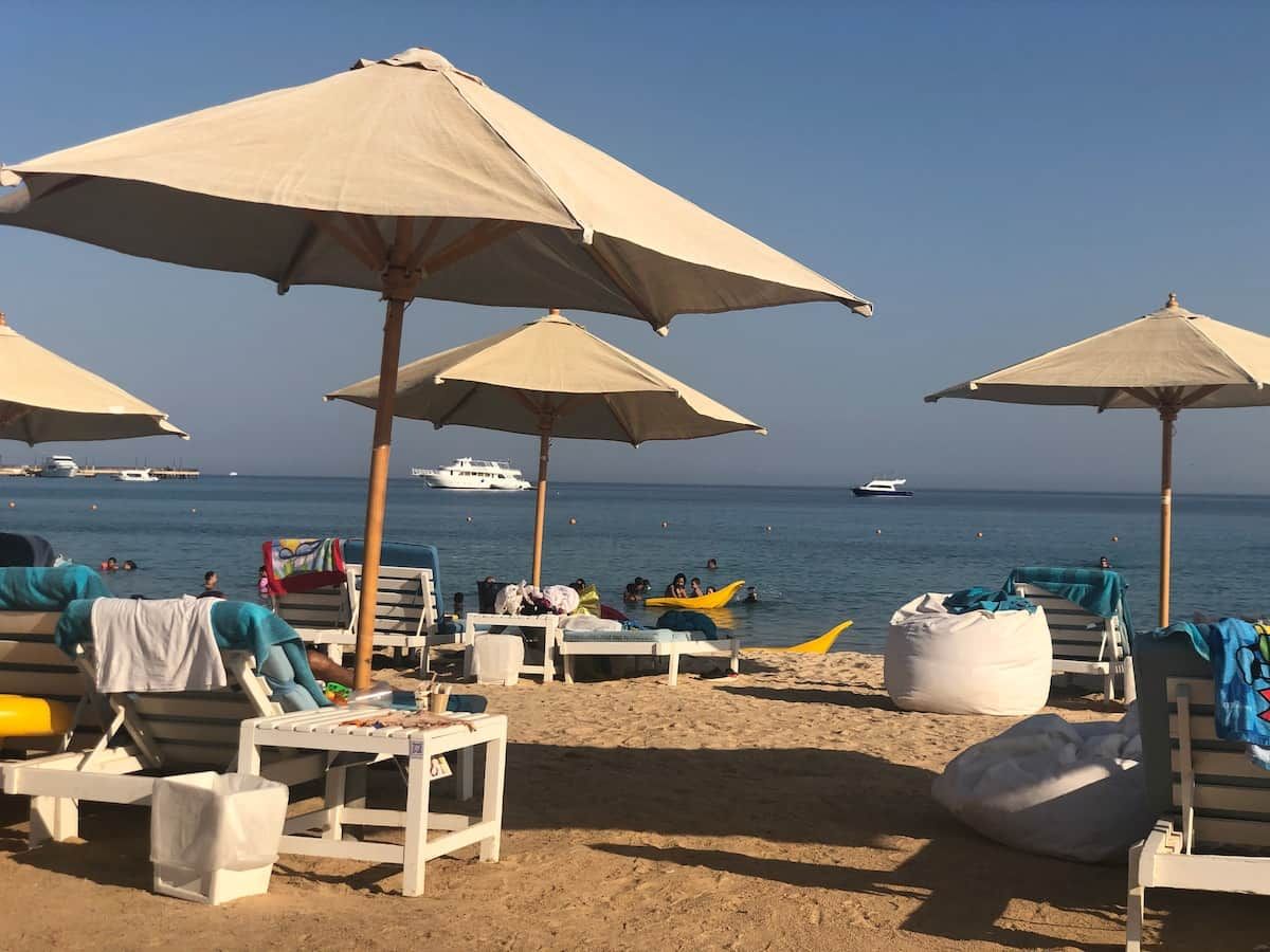Una playa con sombrillas, sillas de descanso y una orilla arenosa.