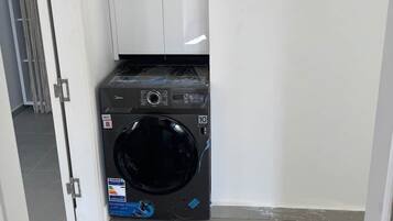 Ein kleiner Hauswirtschaftsraum mit Waschmaschine und weißem Schrank.