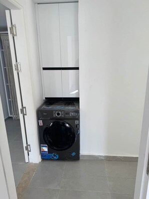 Ein kleiner Hauswirtschaftsraum mit Waschmaschine und weißem Schrank.