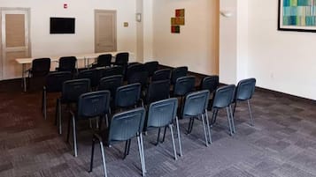A conference room with rows of chairs, a table, and a projector screen.