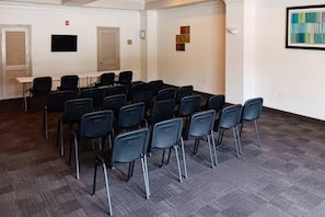 A conference room with rows of chairs, a table, and a projector screen.