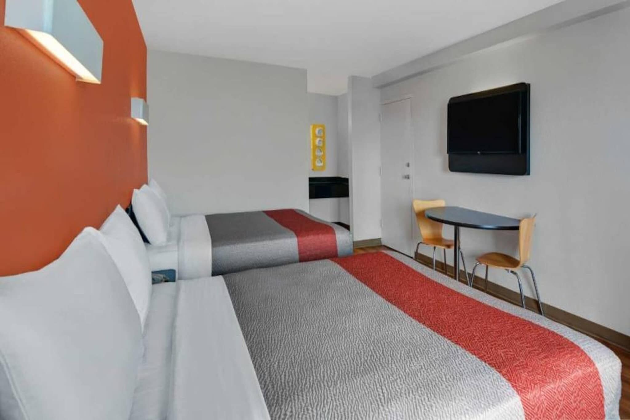 Une chambre d’hôtel avec deux lits, un bureau, une chaise, une télévision et une petite table.