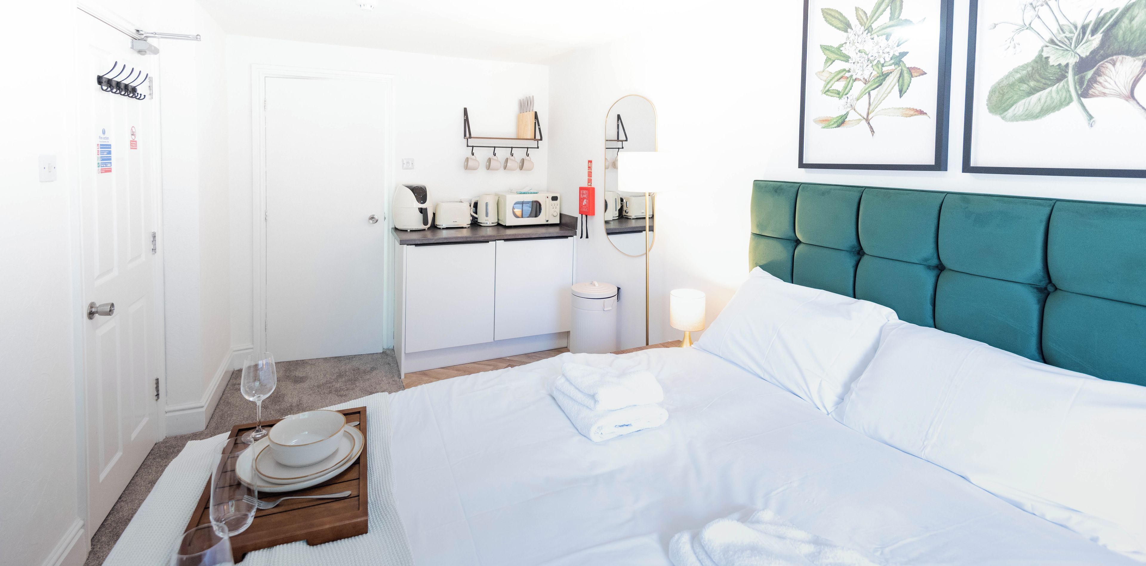 A hotel room with a bed, a small kitchenette, a bathroom, and a dining area.