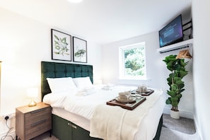 A neatly made bed with white linens, a green upholstered headboard, and a bedside table with a lamp. - The Stanley Arms Hotel by Guestz (Seascale)