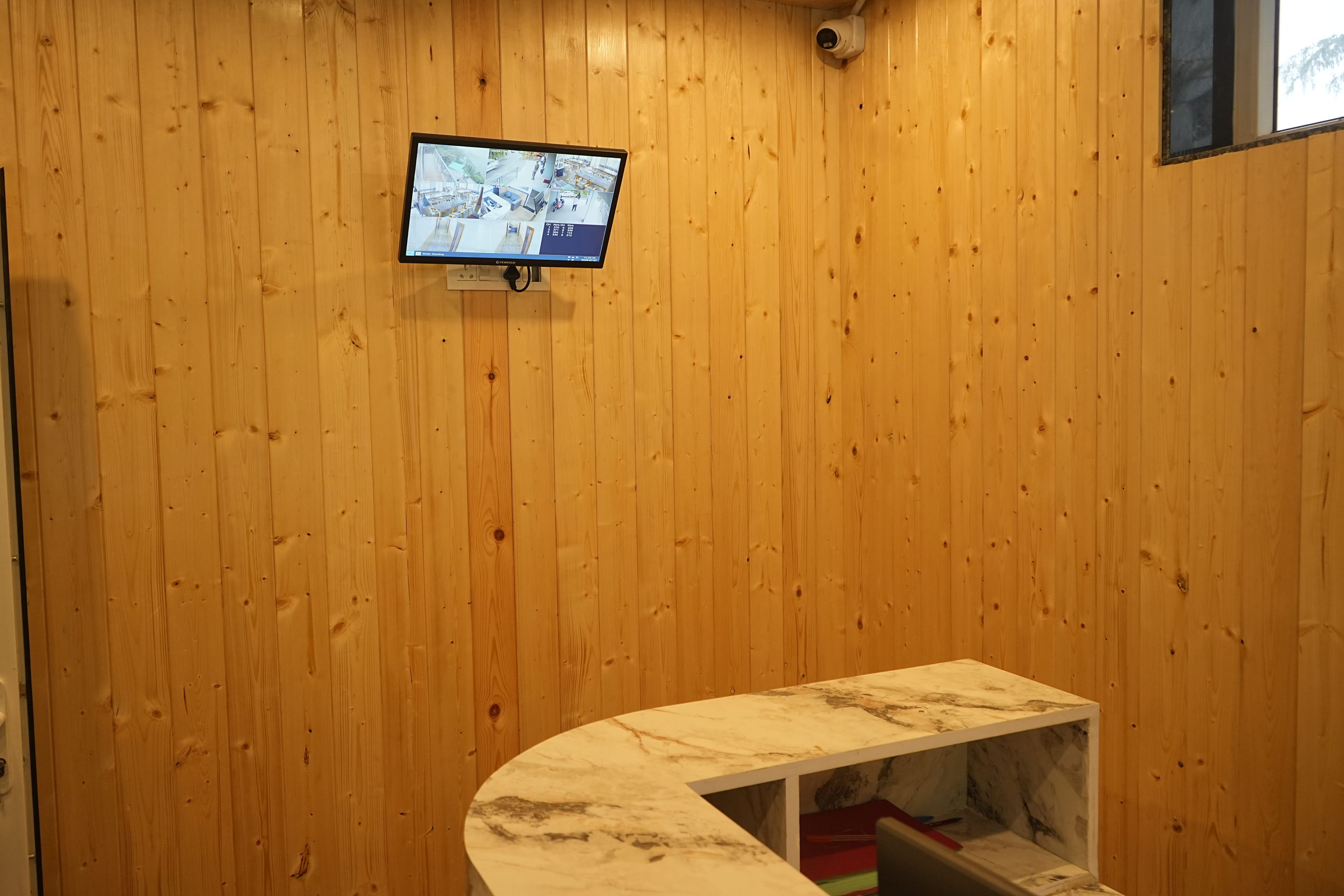 A wooden interior with a round marble table and a mounted security camera.