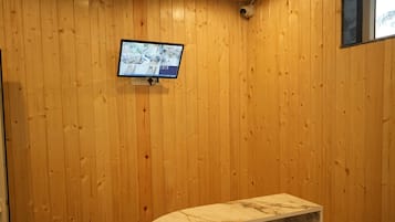A wooden interior with a round marble table and a mounted security camera.