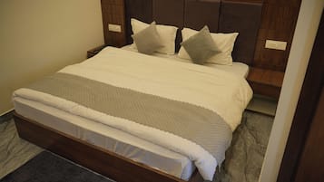 A neatly made bed with a wooden headboard, a grey and white striped blanket, and a grey pillow.