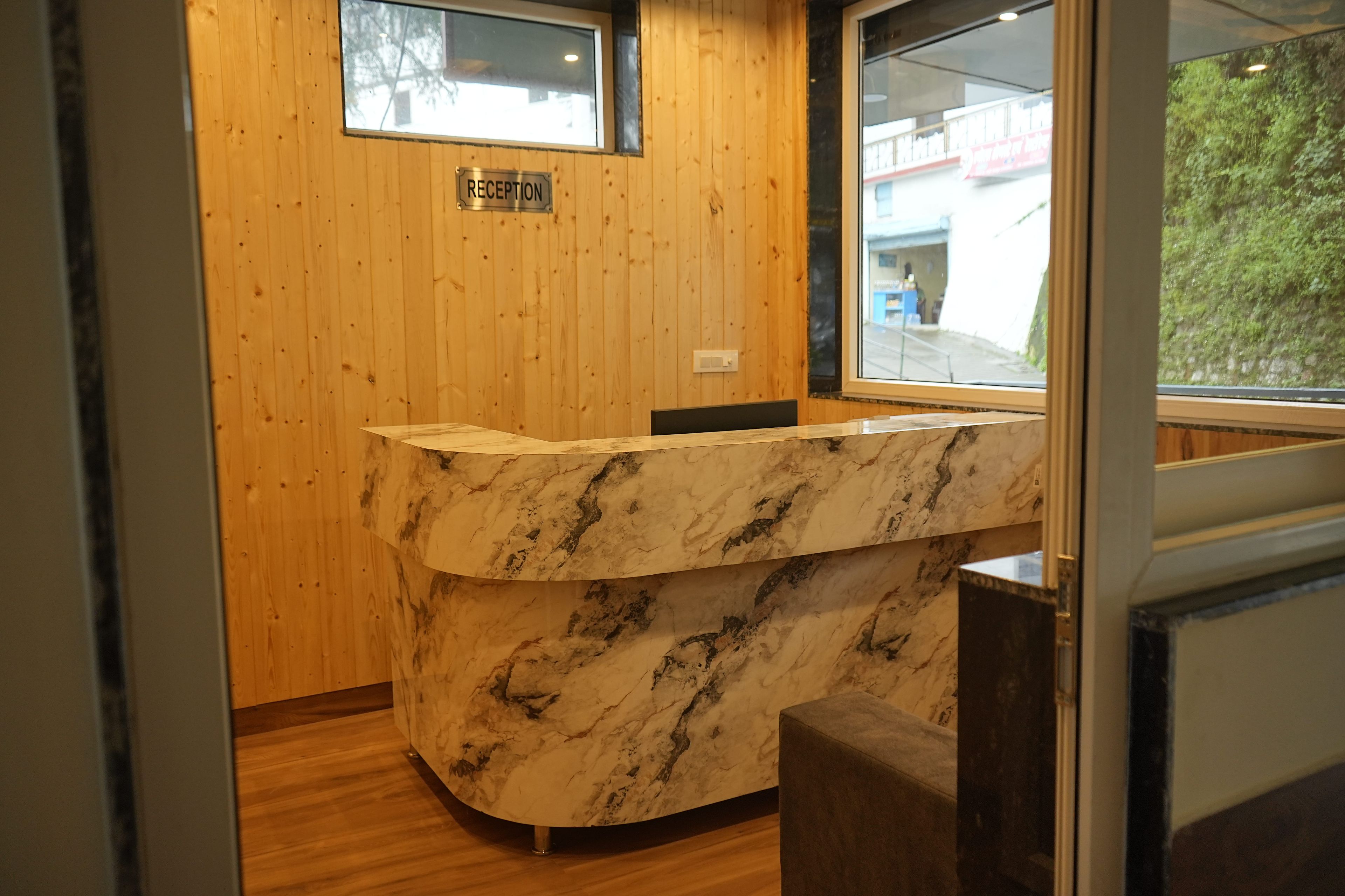 Bancada de recepção com tampo de mármore, painéis de madeira e janela com vista para o exterior.