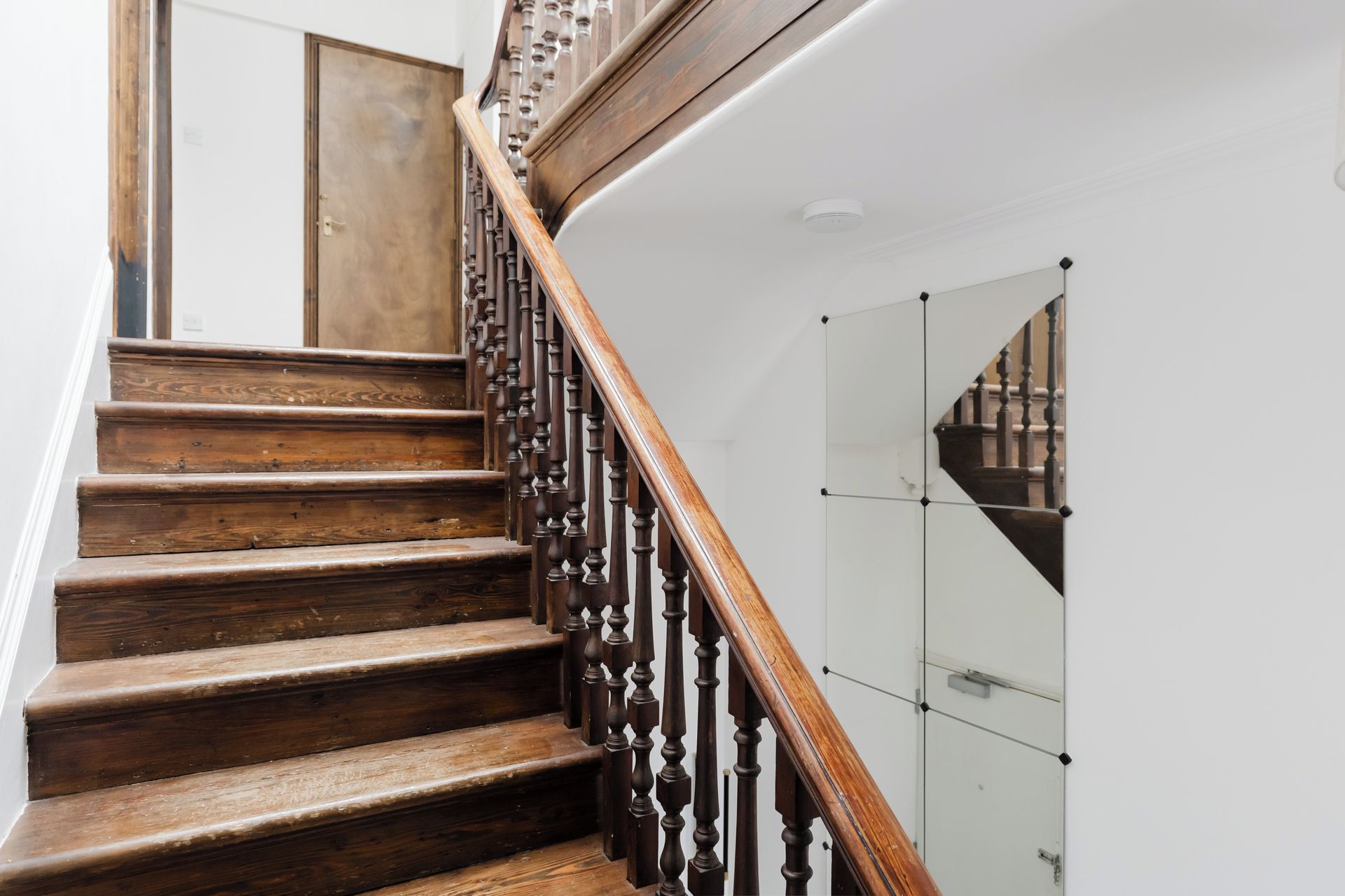 A wooden staircase with a balustrade leading to a landing.