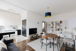 Ein zeitgemäßer Wohnraum mit Küche, Essbereich und Bücherregal.