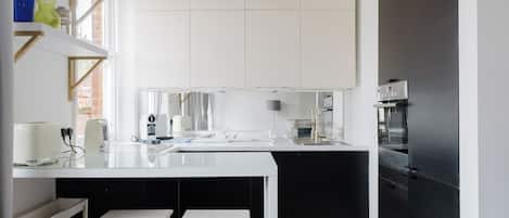 A modern kitchen with white cabinetry, a black countertop, and a built-in oven.