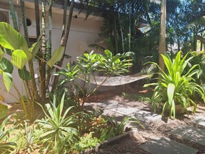 A garden with various tropical plants, a hammock, and a stone pathway. - Fun at the sea - enjoy Strawberry! (Calangute)