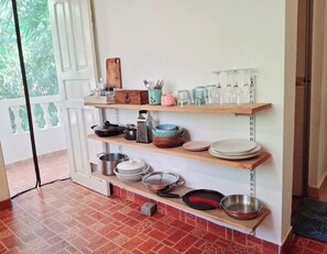 A kitchen with shelves holding cookware, plates, and glassware. - Fun at the sea - enjoy Strawberry! (Calangute)