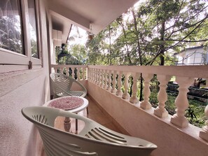 A balcony with a white balustrade, a plastic chair, and a table with a patterned tablecloth. - Fun at the sea - enjoy Strawberry! (Calangute)