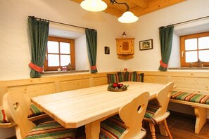 Una mesa de comedor de madera con sillas, un banco y una ventana con cortinas.