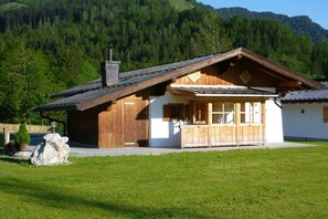 A wooden cabin with a sloped roof, a chimney, and a porch with wooden railings. - & Almhütte "Sonntagshorn" (Unken)