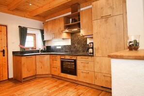A kitchen with wooden cabinets, a built-in oven, and a marble countertop. - & Almhütte "Sonntagshorn" (Unken)
