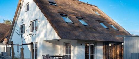Una casa moderna con techo inclinado, ventanas amplias y un espacio de patio.