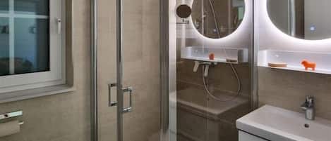 Une salle de bain moderne avec une douche à parois de verre, des toilettes et un lavabo avec un miroir.