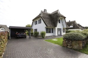 A two-story house with a car parked in a covered garage. - Holiday home with 2 bedrooms (Fuhlendorf)