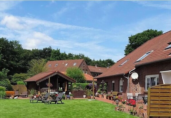 A residential property with a well-maintained lawn, outdoor seating area, and a brick house with a tiled roof. - Holiday apartment with 1 bedroom (Neugaude)
