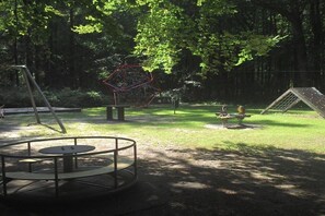 A playground with a swing set, a climbing structure, and a circular seating area. - Holiday apartment with 1 bedroom (Neugaude)