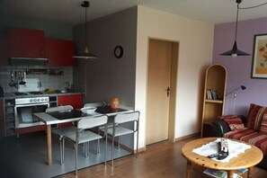 A compact living space with a kitchenette, dining area, and a cozy seating area. - Holiday apartment with 1 bedroom (Neugaude)