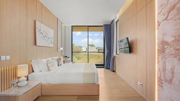 A modern hotel room with a large bed, a desk, and a TV on the wall.