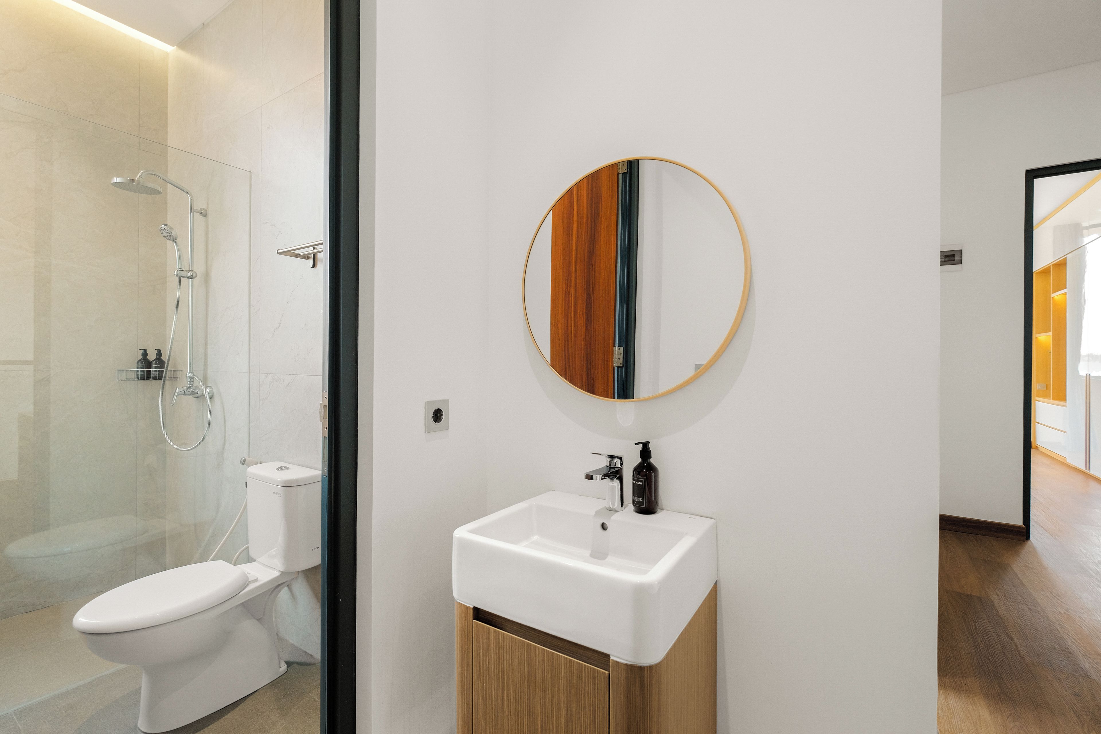 A modern bathroom with a toilet, shower, and sink.
