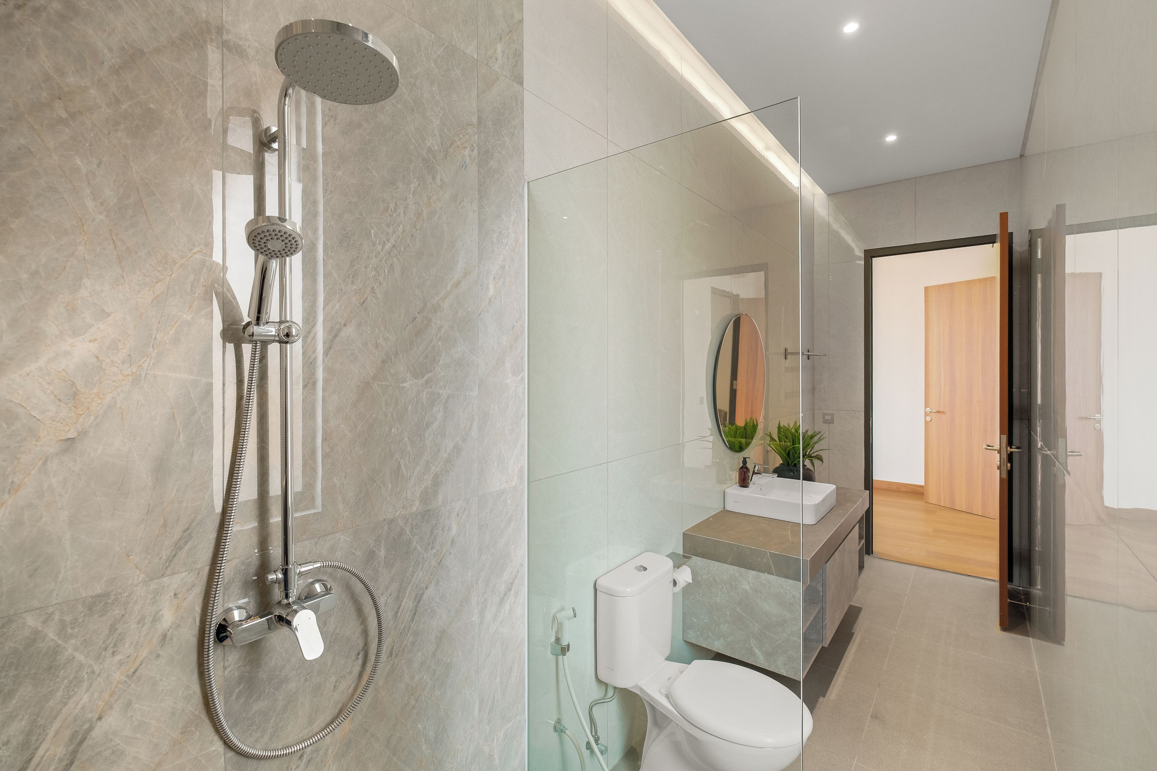 A modern bathroom with a shower, toilet, and sink.