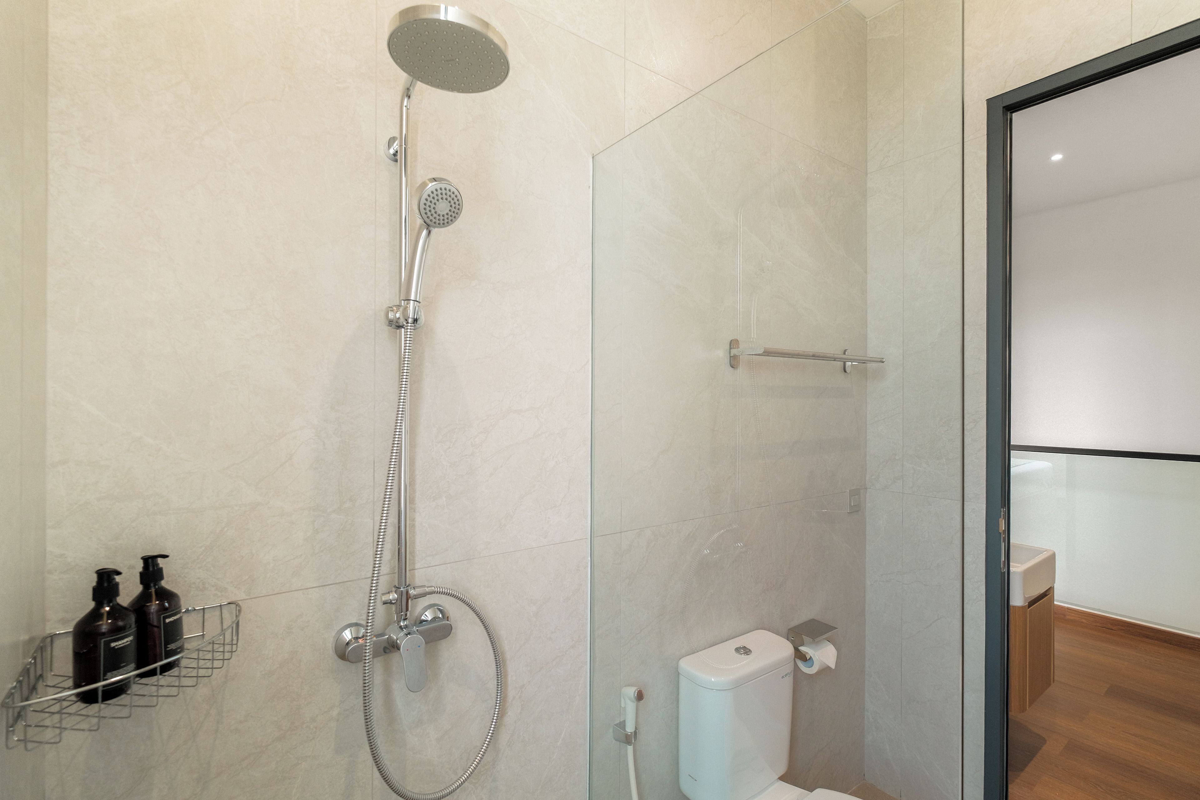 Un baño moderno con ducha, inodoro y mampara de vidrio.