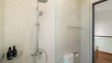 Un baño moderno con ducha, inodoro y mampara de vidrio.