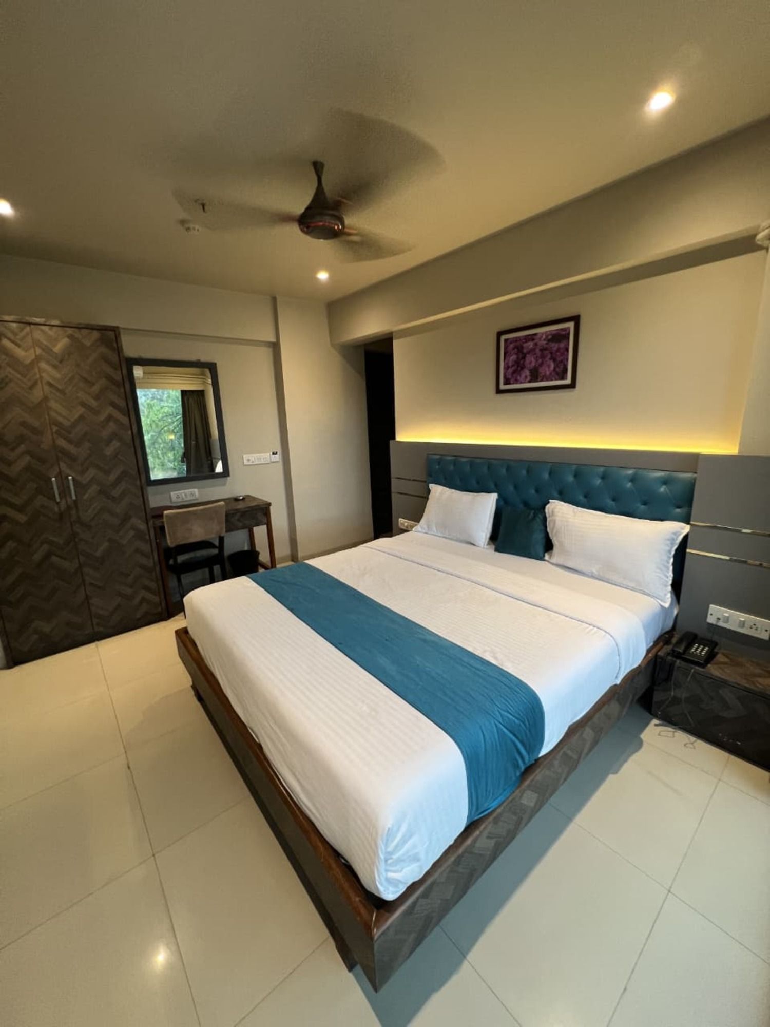 A modern bedroom with a large bed, a desk, and a wardrobe.