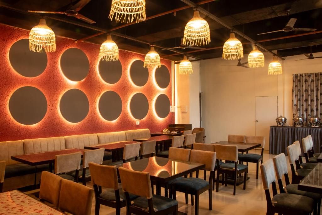 Un restaurante con mesas redondas, cabinas y lámparas colgantes.