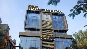 Un moderno edificio de hotel con el nombre 'Hotel JR Residency' visible en la fachada.