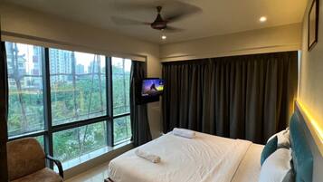 Camera d'albergo con un letto, una TV, una sedia e vista sulla città.