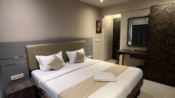 A modern hotel room with a large bed, bedside tables, a desk, and a wardrobe.