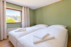 A room with two beds, a window with curtains, and a radiator. - Mountain View Apartment near Winterberg (Winterberg)