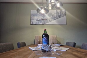 A dining table with a bottle of wine, glasses, and papers. - Mountain View Apartment near Winterberg (Winterberg)